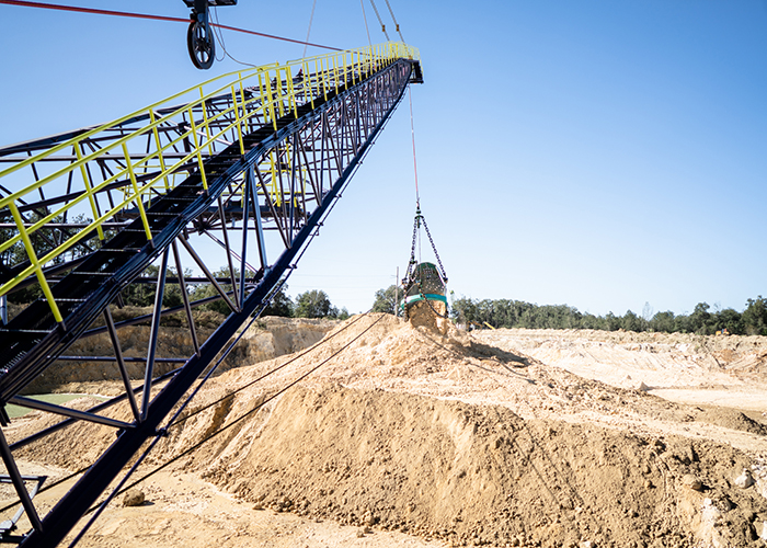 Dragline boom with a bucket of material over a stockpile